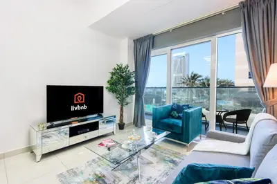 a living room with a tv and a large window at 1BR with Balcony, Steps from JBR & Marina Walk in Dubai