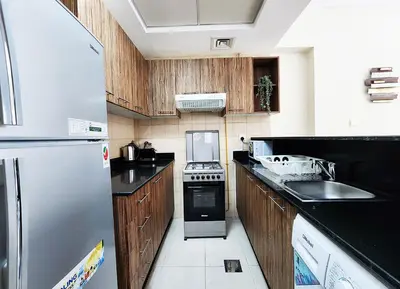 a kitchen with wooden cabinets and a stainless steel refrigerator at RH- Contemporary Living, Studio, Near Burj Khalifa in Dubai