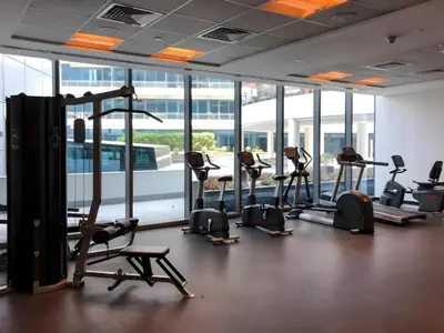a gym with treadmills and ellipticals in a room with windows at Gala Guests - Silverene Tower Marina Living Apartments in Dubai