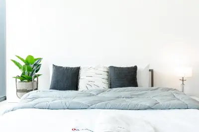 a white bedroom with a bed with blue sheets at Gala Guests - Silverene Tower Marina Living Apartments in Dubai