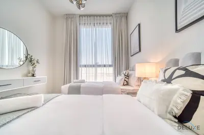 a white bedroom with a large bed and a mirror at Tranquil 2BR with Assistant Room at Mesk 1 Midtown Dubai Production City by Deluxe Holiday Homes in Dubai