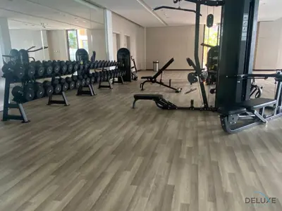 a gym with rows of exercise equipment on a wooden floor at Peaceful 2BR with Assistant Room at Mesk 1 Midtown Dubai Production City by Deluxe Holiday Homes in Dubai