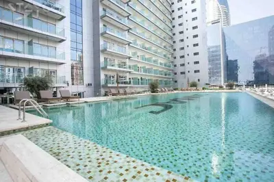 a large swimming pool in a building with tall buildings at 5* Studio, 10min walk to Dubai Mall, 1min Bay Sqr in Dubai