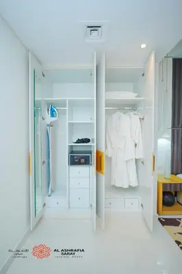 a white bathroom with a closet with white clothes at Alashrafia Saray- Cozy 2BR apartment in Canal Views in Dubai