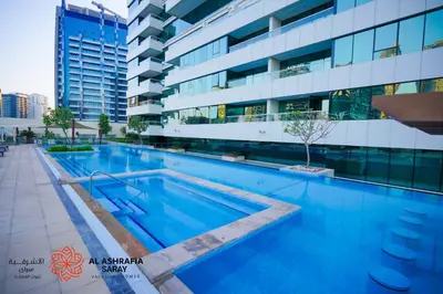a swimming pool in front of a building at Alashrafia Saray- Cozy 2BR apartment in Canal Views in Dubai