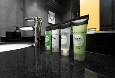 a row of four bottles of sunscreen on a bathroom counter at Izzzi Life Mint in Dubai