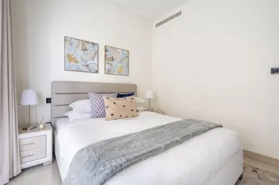 a white bedroom with a large white bed with pillows at GuestReady Holiday Homes - Sobha Urban Retreat in Dubai