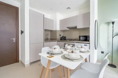 a white kitchen with a white table and chairs at GuestReady Holiday Homes - Sobha Urban Retreat in Dubai