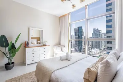 a white bedroom with a large window at GuestReady Holiday Homes - Boho Marina Dream in Dubai