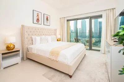 a white bedroom with a bed and a large window at Prime Retreats @ Burj Royale By Emaar in Dubai