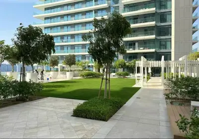 a park in front of a large building at Bright and cozy 1BD apartment on the Beachfront in Dubai