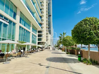 a sidewalk with tables and chairs and a building at Bright and cozy 1BD apartment on the Beachfront in Dubai