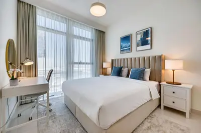 a bedroom with a bed and a desk and a window at Bright and cozy 1BD apartment on the Beachfront in Dubai