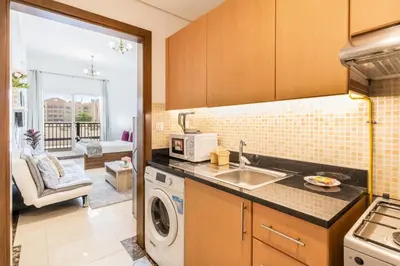 a kitchen with a sink and a washing machine at Lower floor studio with a sofa bed in JVC - Allsopp&Allsopp in Dubai