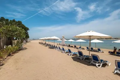 a beach with chairs and umbrellas and the ocean at Spacious 2-bedroom beachfront apartment with pool in Dubai