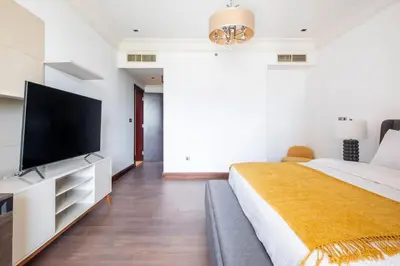 a bedroom with a large bed and a flat screen tv at Spacious 2-bedroom beachfront apartment with pool in Dubai