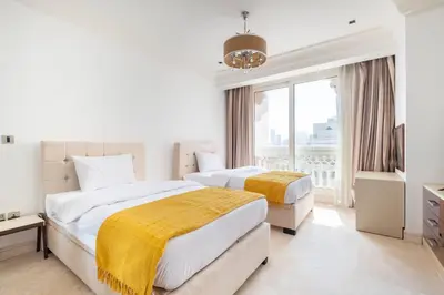 two beds in a white bedroom with a window at Spacious 2-bedroom beachfront apartment with pool in Dubai