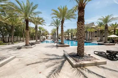 a row of palm trees next to a pool at Spacious 2-bedroom beachfront apartment with pool in Dubai
