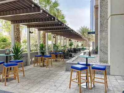 a patio with tables and blue stools at Meera Tower - Sleek One Bedroom in Dubai