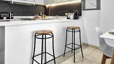 a kitchen with two bar stools at a counter at Serene 1BR with Stunning Marina Views in Dubai Marina - The Atlantic in Dubai
