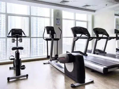 a gym with several tread machines and windows at Serene 1BR with Stunning Marina Views in Dubai Marina - The Atlantic in Dubai