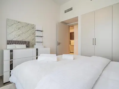 a white bedroom with two beds and white cabinets at Chic 1BR in Park Heights 2 - Dubai Hills in Dubai