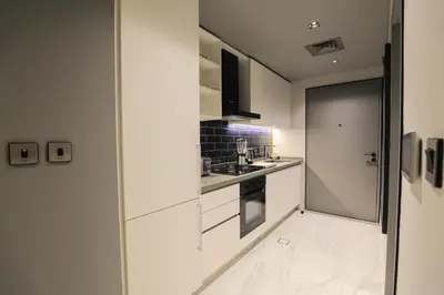 a kitchen with white cabinets and a glass door at Studio - MAG 318 in Dubai