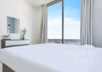 a bedroom with a large white bed and a large window at 2 Bed in Sobha Creek Vista Reserve with Burj Khalifa views hosted by Desert City Stays in Dubai