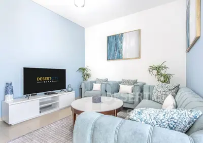a living room with a couch and a tv at 2 Bed in Sobha Creek Vista Reserve with Burj Khalifa views hosted by Desert City Stays in Dubai