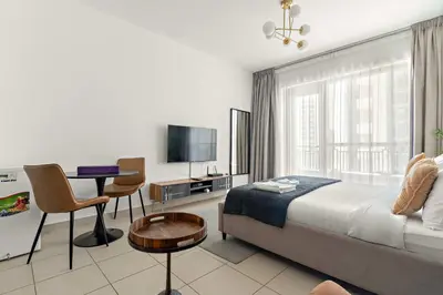 a bedroom with a bed and a table and a tv at Silkhaus spacious studio in Boulevard Central with gym & pool in Dubai