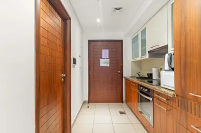 a kitchen with a wooden door and a kitchen counter at Silkhaus spacious studio in Boulevard Central with gym & pool in Dubai
