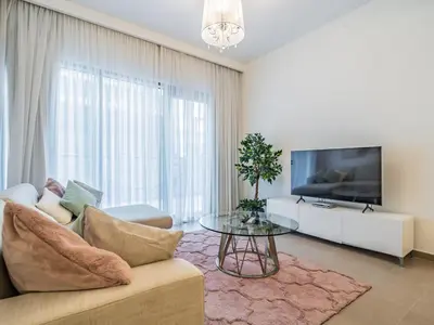 a living room with a couch and a tv and a table at Stylish 1BR in Park Heights 2 - Dubai Hills in Dubai