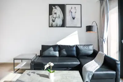 a living room with a black leather couch and pictures of horses at Panoramic Luxe 1BR with Breathtaking Views at Dubai Marina Near JBR - Silverene Towers in Dubai