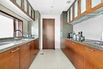 a large kitchen with wooden cabinets and a door at Silkhaus high floor 1BDR in Southridge in Dubai