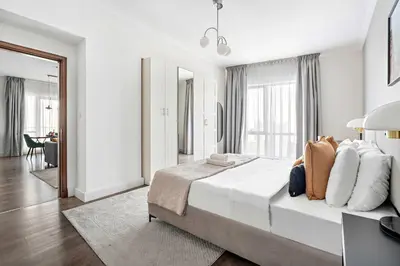 a white bedroom with a large bed and a table at Silkhaus high floor 1BDR in Southridge in Dubai