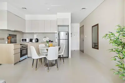 a white kitchen with a table and white chairs at Silkhaus elegant 1BDR in Downtown premium tower in Dubai