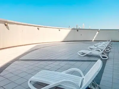 a row of white chairs sitting on a roof at Cosmos Living Luxurious Studio Near Metro in Dubai