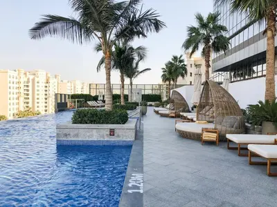 a swimming pool with chairs and palm trees on a building at GuestReady - Bejeweled Studio at The Palm Tower in Dubai