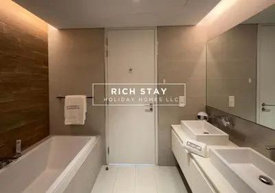 a bathroom with a tub and a sink and a mirror at Crystal Clear 1BR in Blue Waters with Ain View in Dubai