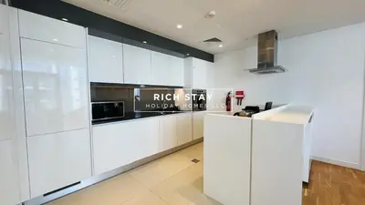 a kitchen with white cabinets and a microwave at Crystal Clear 1BR in Blue Waters with Ain View in Dubai