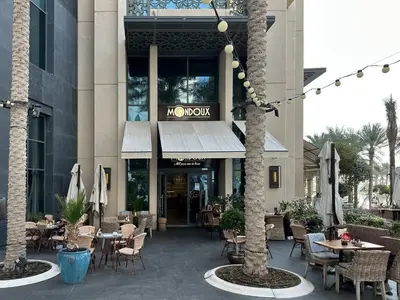 a restaurant with tables and chairs in front of a building at Trophy Lux 2BR Creek Harbour Suites with Iconic Burj Khalifa Views in Dubai