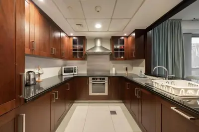 a large kitchen with wooden cabinets and a sink at Bellavista - Dazzling High Floor - 2BR - 29 BOULEVARD - Burj Khalifa & Fountain View in Dubai