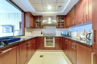 a large kitchen with wooden cabinets and a sink at Bellavista - Splendid - 2BR plus Maid - 29 Boulevard - Burj Khalifa & Fountain in Dubai