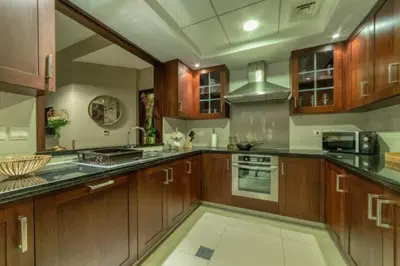 a large kitchen with wooden cabinets and appliances at Bellavista - High Floor - 1BR - 29 Boulevard - Burj Khalifa & Fountain View in Dubai