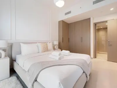 a white bedroom with a large bed with towels on it at Lavishly Elegant 2BR with Breathtaking Full Burj Khalifa View in Dubai
