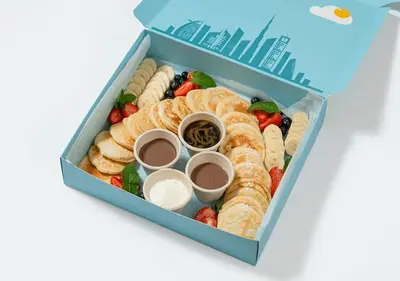 a blue lunch box filled with pastries and fruit at Cosmos Living Stylish Studio Near Marina in Dubai