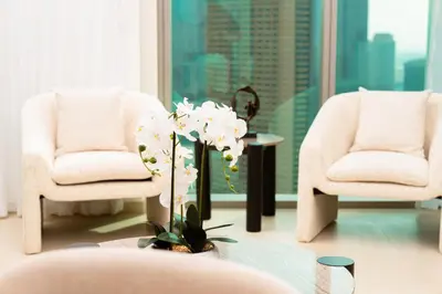 a living room with two chairs and a table with flowers at Prime Retreats @ Downtown Views by Emaar in Dubai