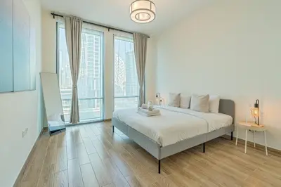 a white bedroom with a bed and large windows at Breathtaking 1Bed with balcony in Al Habtoor city in Dubai