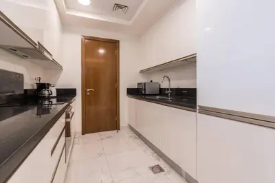 a kitchen with black counter tops and a wooden door at Breathtaking 1Bed with balcony in Al Habtoor city in Dubai