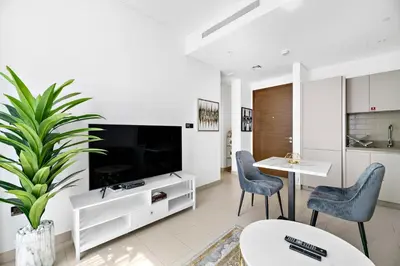 a living room with a large tv and a table and chairs at ALiving Luxury 1BR I Partial Burj khalifa Views I Sobha Creek Vista in Dubai